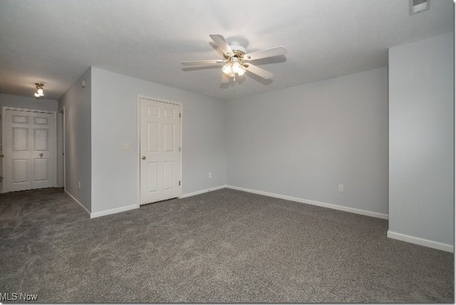 spare room featuring dark carpet, a ceiling fan, and baseboards