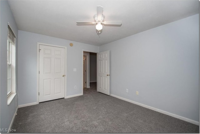 unfurnished bedroom featuring dark colored carpet, baseboards, and ceiling fan