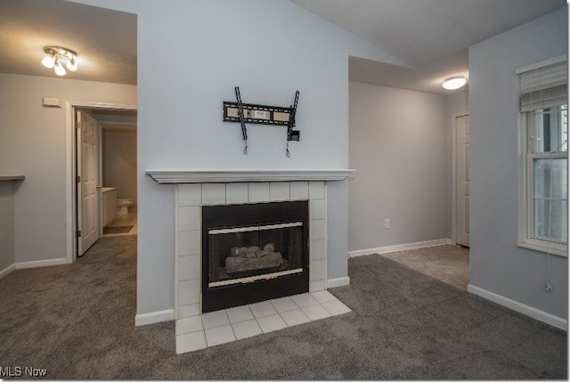 unfurnished living room featuring carpet, a tile fireplace, lofted ceiling, and baseboards