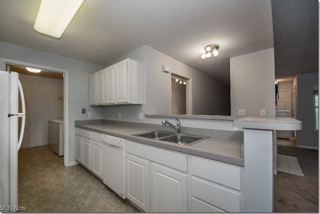 kitchen featuring white appliances, a sink, white cabinetry, washing machine and clothes dryer, and light countertops