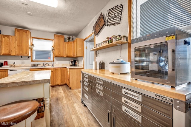 1821 E 30th St, Lorain, OH 44055 - kitchen with light wood finished floors, a textured ceiling, white dishwasher, a sink, and open shelves