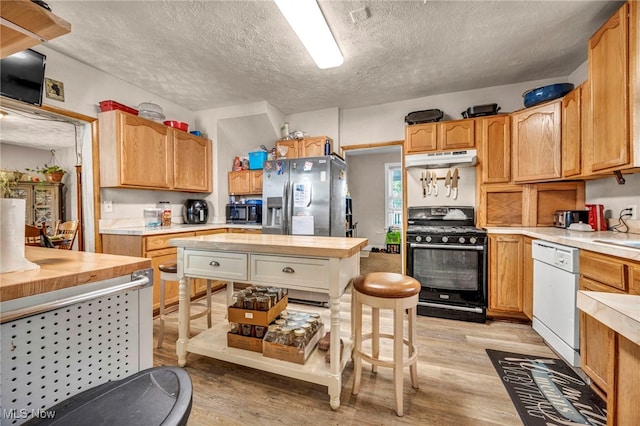 1821 E 30th St, Lorain, OH 44055 - kitchen featuring black gas range oven, white dishwasher, under cabinet range hood, a textured ceiling, and light wood-type flooring