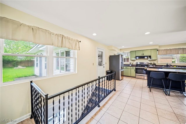 kitchen with green cabinets, stainless steel appliances, under cabinet range hood, recessed lighting, and light tile patterned floors