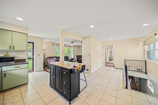 kitchen featuring stainless steel microwave, green cabinets, light tile patterned floors, healthy amount of natural light, and recessed lighting