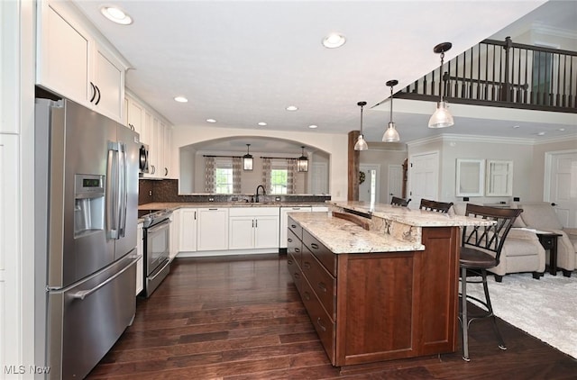 1152 Terraho Dr, Salem, OH 44460 - kitchen featuring appliances with stainless steel finishes, open floor plan, ornamental molding, a kitchen bar, and arched walkways