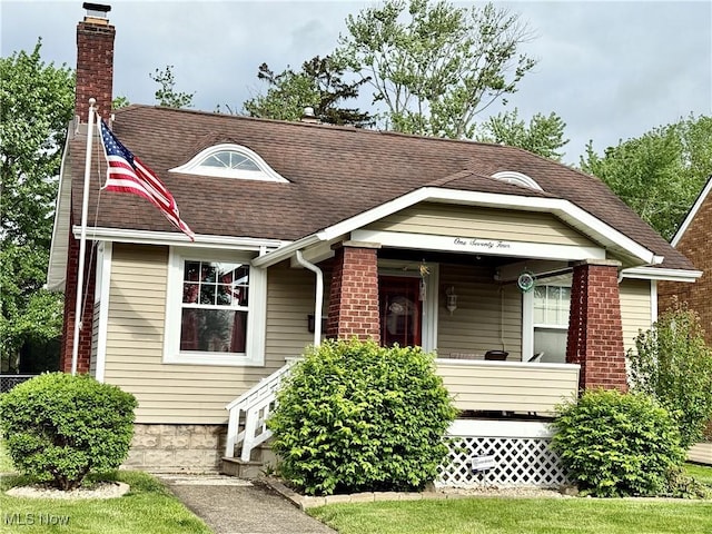 view of front of property with a chimney, roof with shingles, and covered porch