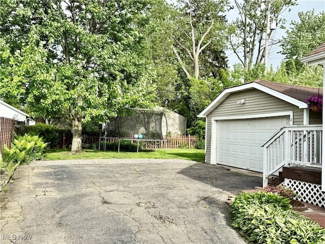 detached garage featuring a trampoline and fence