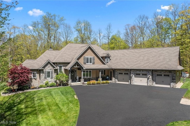15020 Steelhead Run, Chardon, OH 44024 - view of front of property featuring stone siding, an attached garage, driveway, a front lawn, and roof with shingles