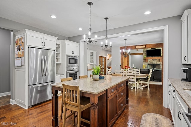 15020 Steelhead Run, Chardon, OH 44024 - kitchen with built in appliances, a chandelier, dark wood finished floors, white cabinetry, and a fireplace
