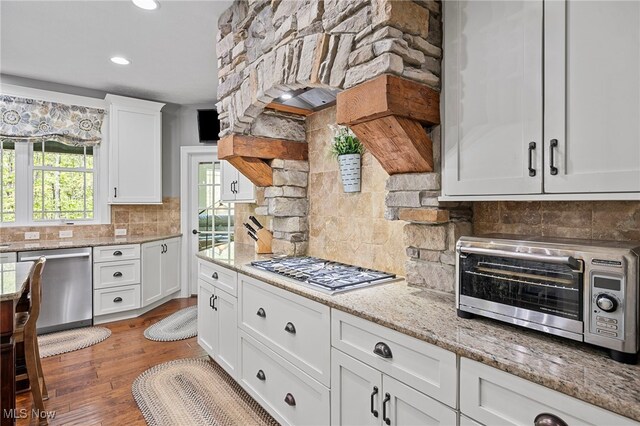 15020 Steelhead Run, Chardon, OH 44024 - kitchen featuring appliances with stainless steel finishes, white cabinetry, decorative backsplash, light stone countertops, and wood finished floors