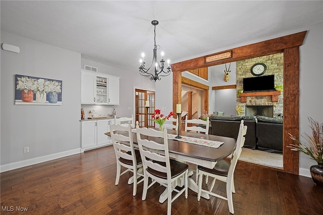 15020 Steelhead Run, Chardon, OH 44024 - dining room featuring dark wood-style floors, a chandelier, baseboards, and a stone fireplace