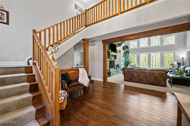15020 Steelhead Run, Chardon, OH 44024 - staircase featuring a towering ceiling, hardwood / wood-style flooring, a stone fireplace, and baseboards