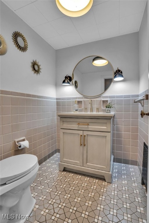 555 E Milton St, Alliance, OH 44601 - bathroom featuring tile walls, tile patterned flooring, wainscoting, toilet, and vanity