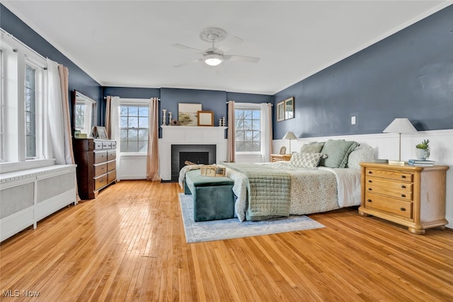 555 E Milton St, Alliance, OH 44601 - bedroom with wood finished floors, a fireplace with flush hearth, radiator heating unit, crown molding, and a ceiling fan