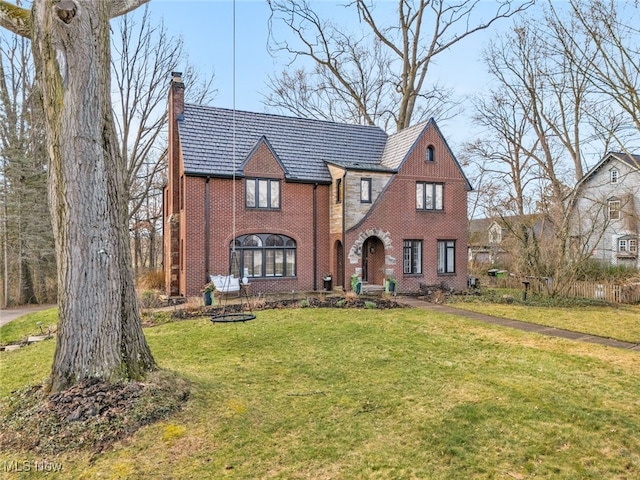 555 E Milton St, Alliance, OH 44601 - tudor home featuring a chimney, brick siding, a front lawn, and a high end roof