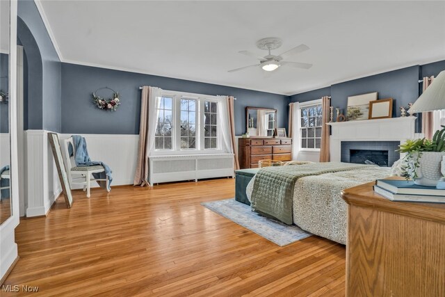 555 E Milton St, Alliance, OH 44601 - bedroom with a wainscoted wall, a fireplace, light wood-type flooring, arched walkways, and ceiling fan
