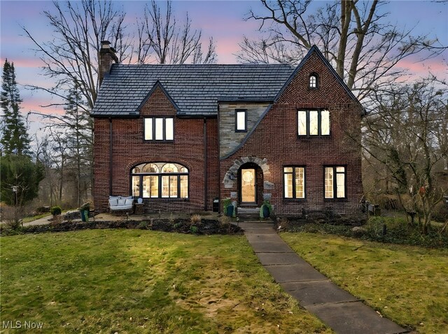 555 E Milton St, Alliance, OH 44601 - tudor home with a high end roof, a chimney, brick siding, and a lawn