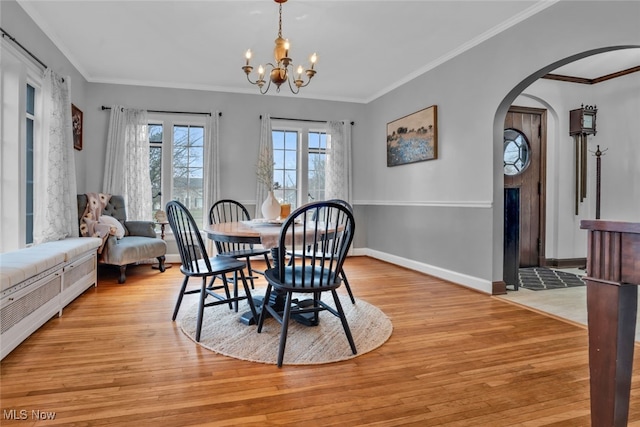 555 E Milton St, Alliance, OH 44601 - dining area featuring light wood-style floors, crown molding, a chandelier, arched walkways, and baseboards