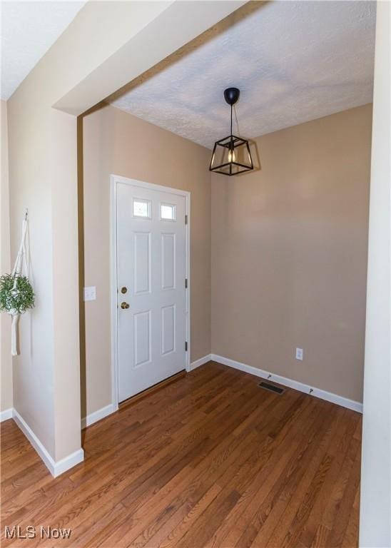 entrance foyer featuring baseboards, wood finished floors, and a chandelier