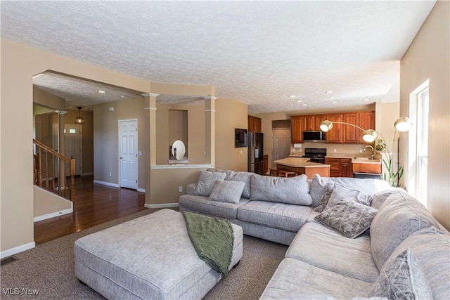 living area with stairway, baseboards, a textured ceiling, recessed lighting, and dark colored carpet