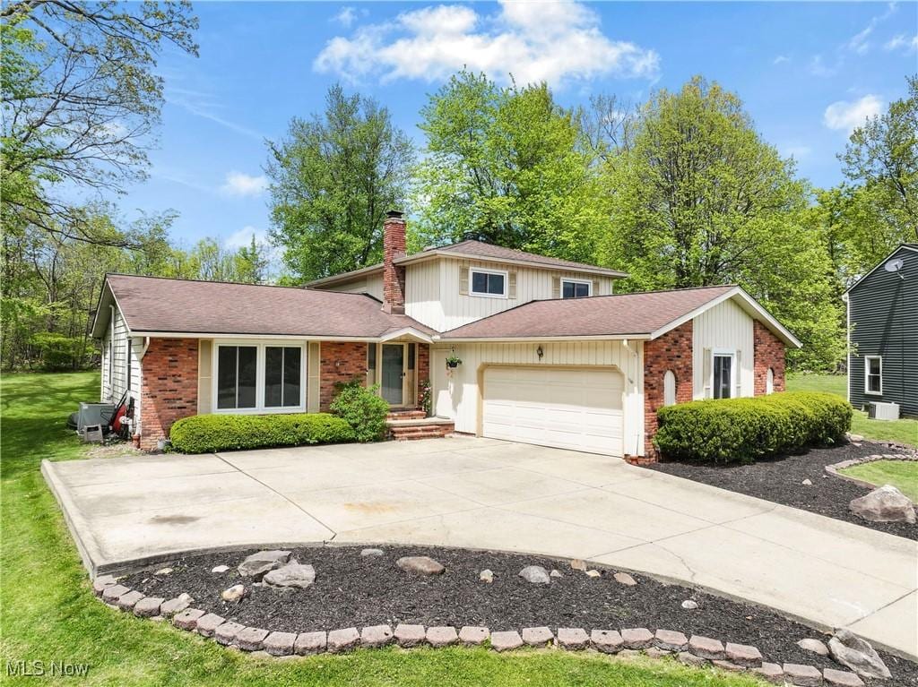 31965 Tracy Ln, Solon, OH 44139 - traditional home with a chimney, brick siding, an attached garage, driveway, and a front yard
