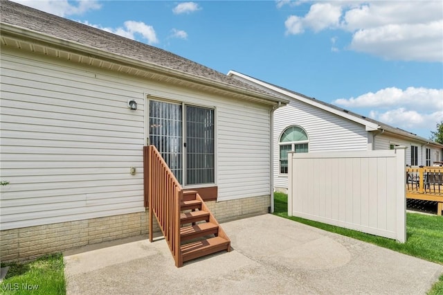 rear view of property with entry steps, a patio area, and roof with shingles