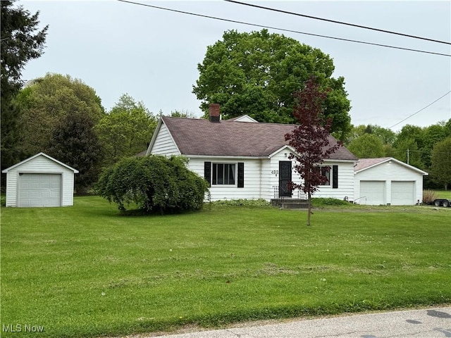 view of front of house featuring a detached garage, an outdoor structure, a front lawn, and a chimney