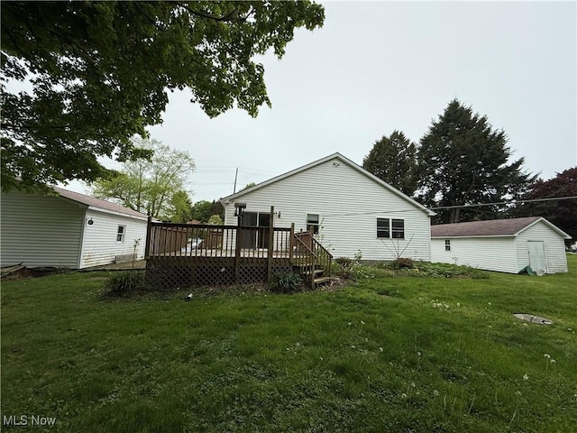 rear view of house with a deck, a yard, and an outdoor structure