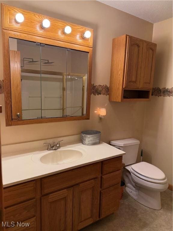 bathroom featuring vanity, toilet, and a shower with shower door