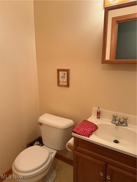 half bathroom featuring toilet, vanity, and baseboards