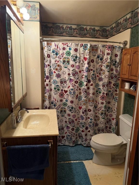 bathroom featuring toilet, vanity, a shower with shower curtain, and tile patterned flooring