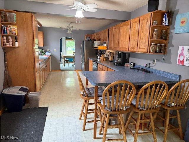 kitchen featuring open shelves, range with electric stovetop, ceiling fan, freestanding refrigerator, and beamed ceiling