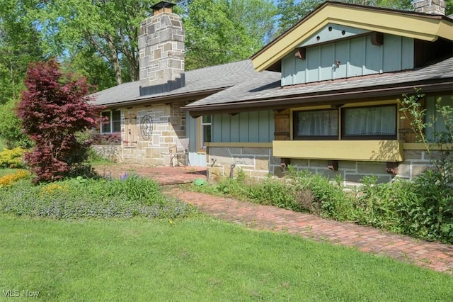 31 Garden Park Dr, Chagrin Falls, OH 44022 - view of front facade with a chimney, board and batten siding, a front yard, stone siding, and a shingled roof