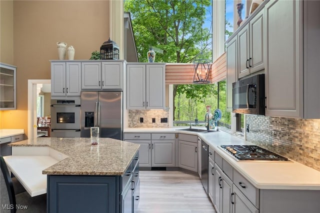 540 Bent Creek Oval, Aurora, OH 44202 - kitchen featuring appliances with stainless steel finishes, a sink, tasteful backsplash, a kitchen island, and light wood-type flooring
