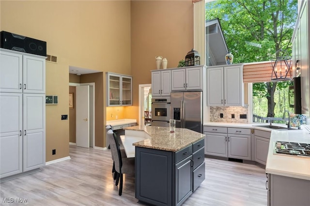 540 Bent Creek Oval, Aurora, OH 44202 - kitchen featuring stainless steel appliances, gray cabinetry, light wood-style floors, a high ceiling, and a center island