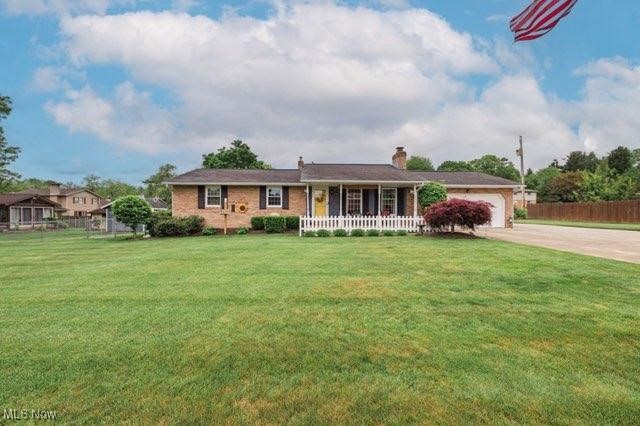 1547 Radcliff Ave NW, Massillon, OH 44646 - ranch-style house with concrete driveway, an attached garage, covered porch, and a chimney