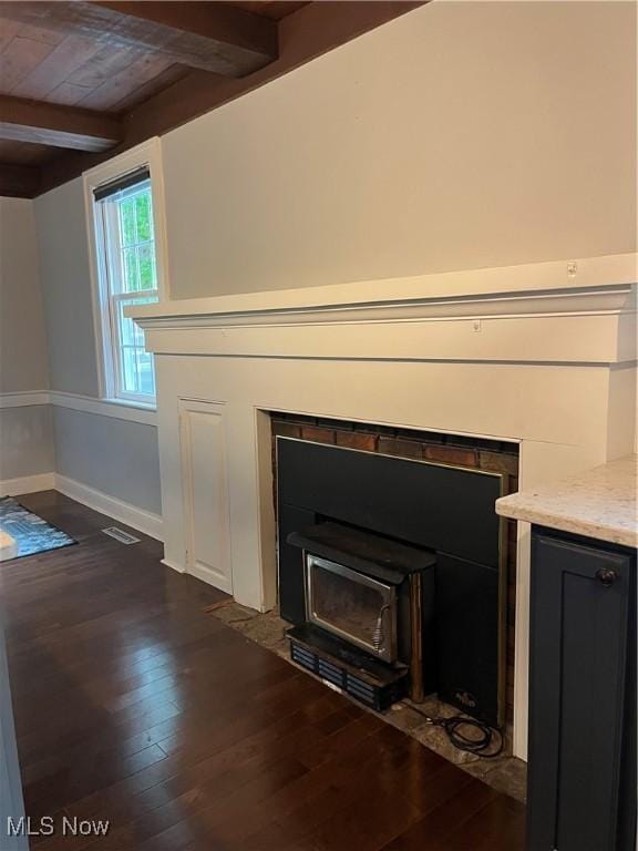 detailed view of wood finished floors, baseboards, and a wood stove