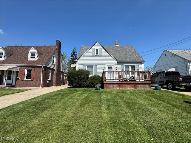 rear view of property with a wooden deck, a lawn, a chimney, and brick siding