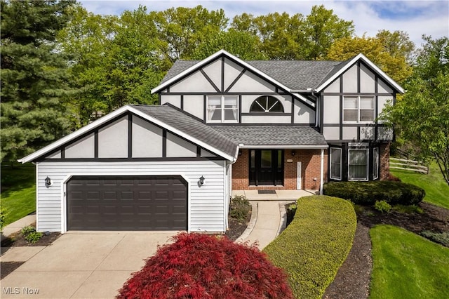 21428 Montclare Blvd, Strongsville, OH 44149 - tudor house with a shingled roof, brick siding, an attached garage, driveway, and a porch