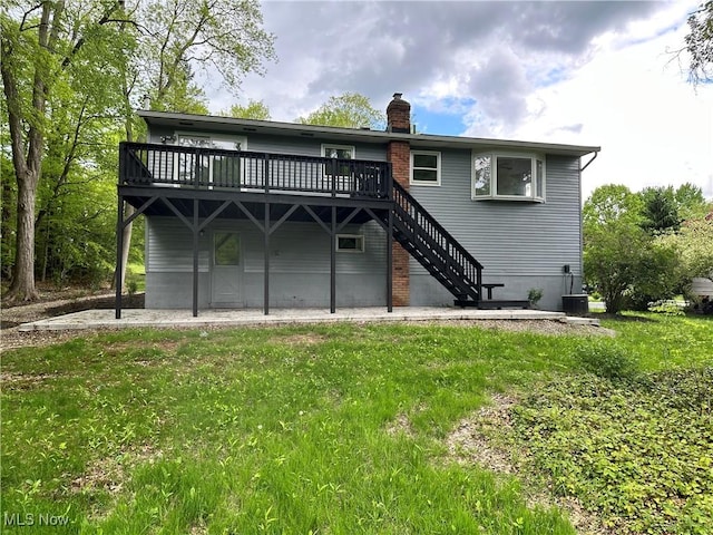 9744 Andrea Dr, Concord, OH 44060 - rear view of house featuring a wooden deck, a chimney, a patio area, stairway, and a lawn