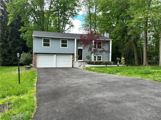 9744 Andrea Dr, Concord, OH 44060 - bi-level home featuring asphalt driveway, a chimney, a garage, brick siding, and a front lawn