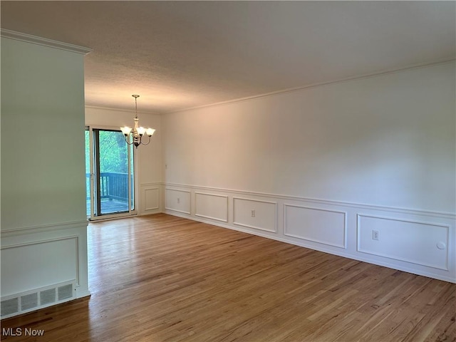 9744 Andrea Dr, Concord, OH 44060 - spare room featuring a chandelier, a decorative wall, ornamental molding, wood finished floors, and wainscoting