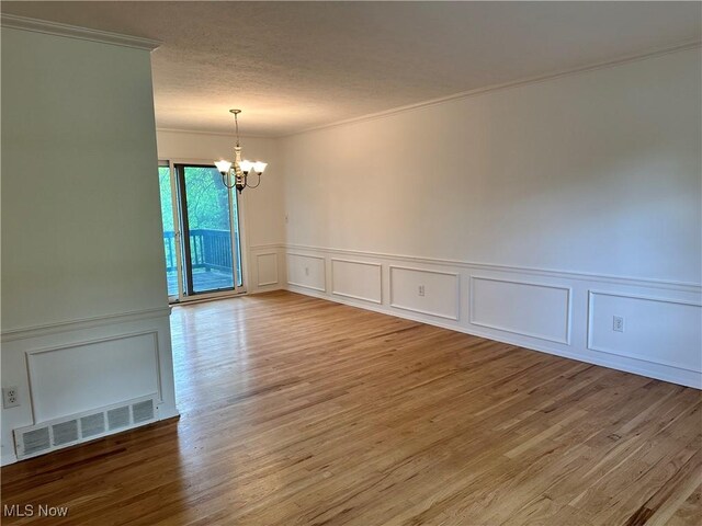 9744 Andrea Dr, Concord, OH 44060 - empty room featuring a decorative wall, a chandelier, ornamental molding, light wood finished floors, and a wainscoted wall