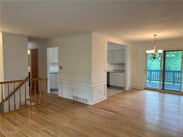9744 Andrea Dr, Concord, OH 44060 - unfurnished room featuring a chandelier, crown molding, light wood finished floors, a decorative wall, and a wainscoted wall