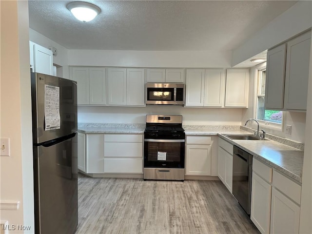 9744 Andrea Dr, Concord, OH 44060 - kitchen with stainless steel appliances, a sink, light wood-style flooring, light countertops, and a textured ceiling