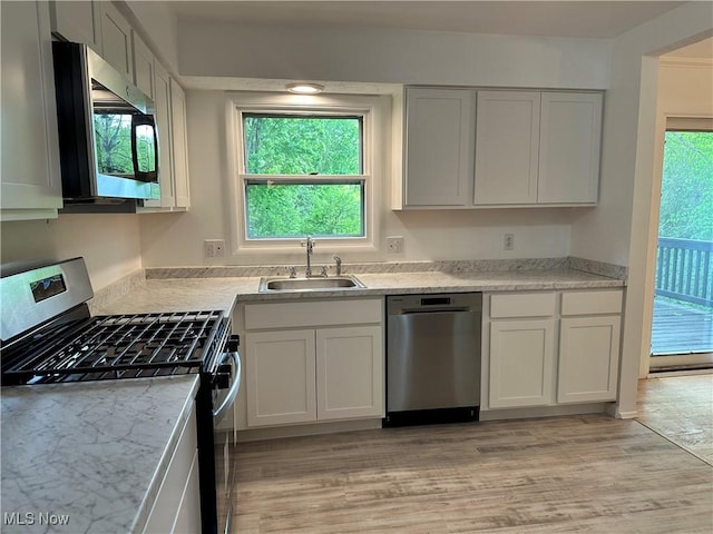 9744 Andrea Dr, Concord, OH 44060 - kitchen featuring stainless steel appliances, a sink, light wood-style floors, and white cabinets