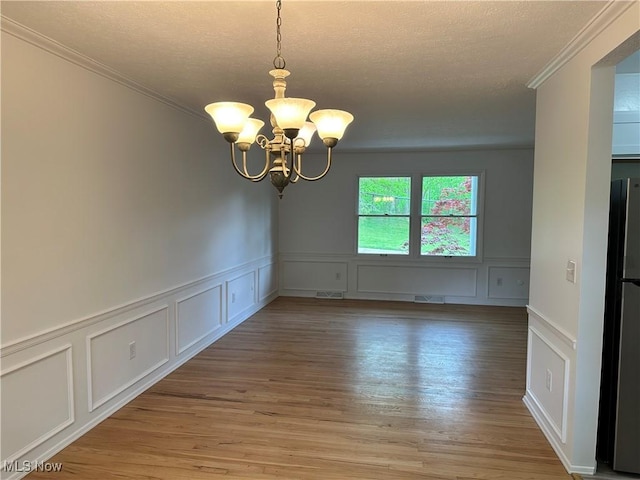 9744 Andrea Dr, Concord, OH 44060 - unfurnished room with a decorative wall, a chandelier, ornamental molding, light wood finished floors, and a textured ceiling