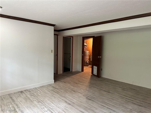 9744 Andrea Dr, Concord, OH 44060 - unfurnished room featuring water heater, ornamental molding, light wood finished floors, baseboards, and a textured ceiling