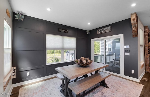 dining room with a decorative wall, wood finished floors, recessed lighting, and baseboards