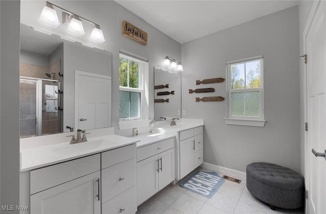 bathroom featuring a stall shower, two vanities, tile patterned flooring, and baseboards